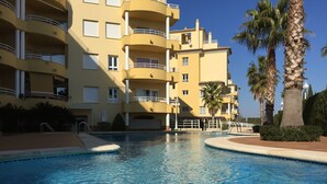 Zona de piscina con un edificio de varios pisos al fondo.