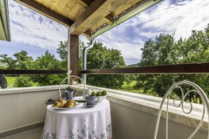 A balcony with a table set for breakfast, overlooking a green landscape. - Village stone Villa Ana Boljun (Boljun)