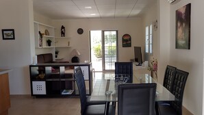A dining area with a glass table and black chairs, a white desk with a lamp, and a view of the outdoors through a large window. - Excelent house in front of Golf filds / privat pool (Alicante)