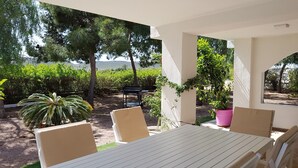 An outdoor patio with a table and chairs, surrounded by greenery and a view of the sea. - Excelent house in front of Golf filds / privat pool (Alicante)