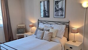 A neatly made bed with a white comforter and multiple pillows, flanked by two bedside tables with lamps, in a room with tiled flooring and two framed pictures on the wall. - fantastically located detached villa with private swimming pool for 8 people. (Callas)