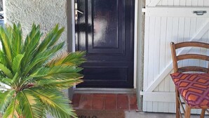 A black door with a white frame, a white sliding door, a potted plant, and a chair with a patterned cushion. - fantastically located detached villa with private swimming pool for 8 people. (Callas)