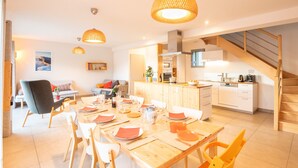 A modern kitchen with wooden cabinets, a dining area with a wooden table set for six, and a staircase leading to an upper level. - Facing south, garden, exceptional view, super equipped. Ideal for 2 families (Lans-en-Vercors)