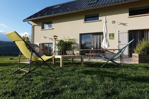 Une maison dotée d’un patio comprenant une table, des chaises et une pergola.