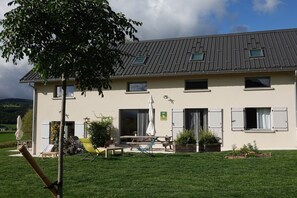 Un bâtiment à deux étages, doté d’un toit plat, de grandes fenêtres et d’un patio aménagé avec du mobilier d’extérieur.