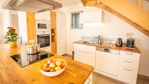 A modern kitchen with wooden cabinets, a stainless steel sink, and a built-in oven. - Facing south, garden, exceptional view, super equipped. Ideal for 2 families (Lans-en-Vercors)