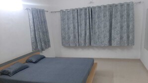 A bedroom with a wooden bed frame, a grey mattress, and matching grey curtains. - 150 Kalhaar Blues Greens- Golfers retreat. (Vasna Iyava)