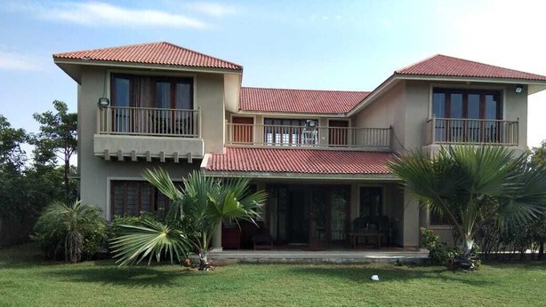 A two-story house with a red-tiled roof, balconies, and a well-maintained lawn. - 150 Kalhaar Blues Greens- Golfers retreat. (Vasna Iyava)