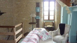 Une chambre rustique avec un lit en bois, une chaise, une petite table et une fenêtre donnant sur un beau paysage.