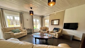A living room with leather sofas, a coffee table, a fireplace, and a TV mounted on the wall. - Unique vacation home with a hot tub in nature (Meeuwen-Gruitrode)