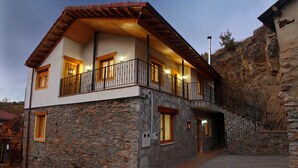 Un edificio in pietra di due piani, con un balcone, una scala e un'apertura che conduce all'ingresso.