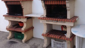 Two outdoor brick pizza ovens against a white wall. - Lara Apartment (Albufeira)
