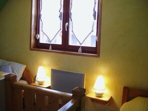 Een slaapkamer met een bed, twee nachtkastjes met lampen, een raam met gordijnen en een houten hoofdeinde.