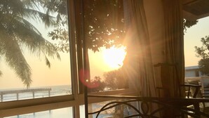 Ein Schlafzimmer mit Meerblick bei Sonnenuntergang, ein Bett und ein Sessel in der Nähe des Fensters.