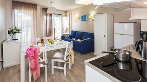Ein kompaktes Hotelzimmer mit Küchenzeile, Essbereich und Wohnbereich.