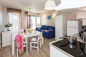Ein kompaktes Hotelzimmer mit Küchenzeile, Essbereich und Wohnbereich.