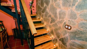 Un escalier en bois doté d’un éclairage intégré, menant à un mur en pierre.