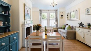 A cozy dining area with a wooden table, white chairs, and a blue cabinet. - Bikki Apartments, Bikki Apartments (Harrow)