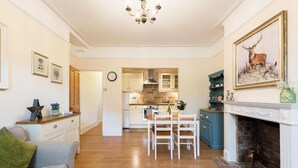 A spacious living room with a fireplace, a dining area, and a kitchen in the background. - Bikki Apartments, Bikki Apartments (Harrow)