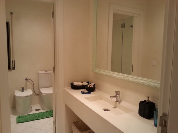 A bathroom with a white sink, a mirror, a towel rack, and a shower area.