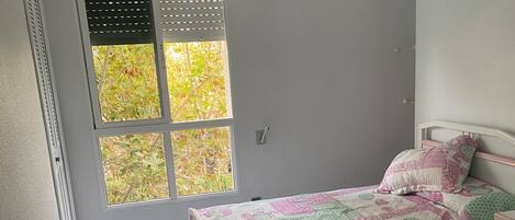 A bedroom with two beds, a window with blinds, a ceiling fan, and a tiled floor.