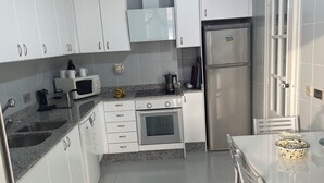 Una cucina moderna con mobili bianchi, un frigorifero in acciaio inossidabile, un forno a microonde e un piano cottura a gas.