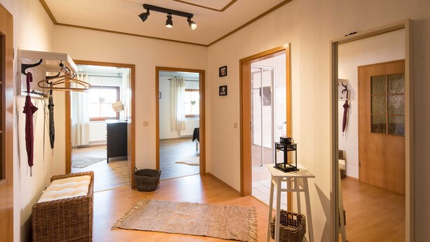 A hallway with a wicker bench, a small table with a lamp, and a mirror on the wall. - Vacation apartment Ziske, Germany (Bad Wildungen)