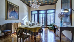 A dining room with a wooden table set for four, a chandelier, and a large painting on the wall. - RABOSO Grand 9~windows (Venezia)