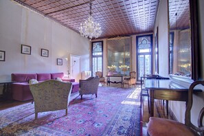 A room with a patterned carpet, a purple sofa, and a chandelier. - RABOSO Grand 9~windows (Venezia)