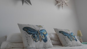 A bedroom with a bed, two decorative pillows with butterfly designs, a wall star, and a bedside lamp. - Cozy apartment in Alp with garden and parking, 10 minutes from the ski slopes! (Alp)