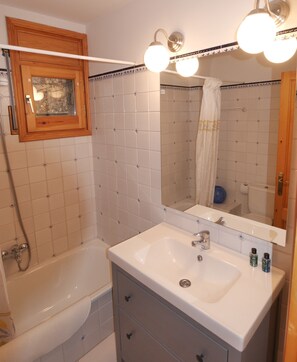 A bathroom with a bathtub, a sink with a mirror, and a shower. - Cozy apartment in Alp with garden and parking, 10 minutes from the ski slopes! (Alp)