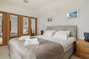 Une chambre d’hôtel avec un grand lit, une armoire, une table de chevet et deux tableaux encadrés au mur.