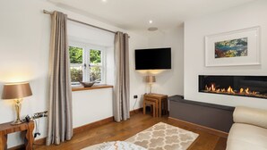 A modern bedroom with a fireplace, a TV mounted on the wall, and a window with curtains.