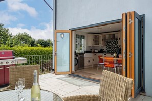 Un patio descubierto con una mesa, sillas y una parrilla.