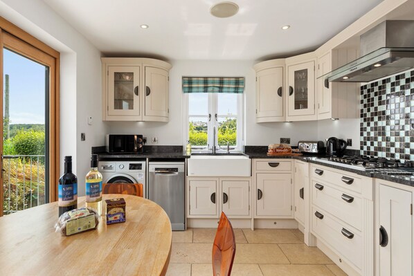 A modern kitchen with a dining area, featuring a large window, built-in appliances, and a view of the outdoors.