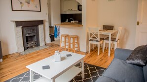 A living room with a fireplace, a dining area with a table and chairs, and a kitchen area with a counter and stools. - Toothbrush Apartments - Central Ipswich - Fonnereau Rd (Ipswich)