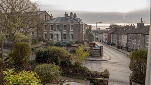 A residential street with houses, a roundabout, and a large building with a prominent entrance. - Toothbrush Apartments - Central Ipswich - Fonnereau Rd (Ipswich)