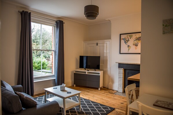 Una sala de estar moderna con sofá, mesa, televisor y chimenea.