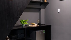 A modern bedroom with a bed, a desk with a plant, a shelf, and a poster on the wall.