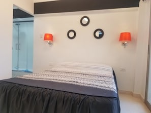 Ein Schlafzimmer mit einem Bett, zwei Wandleuchten und einer Tür zu einem Badezimmer.