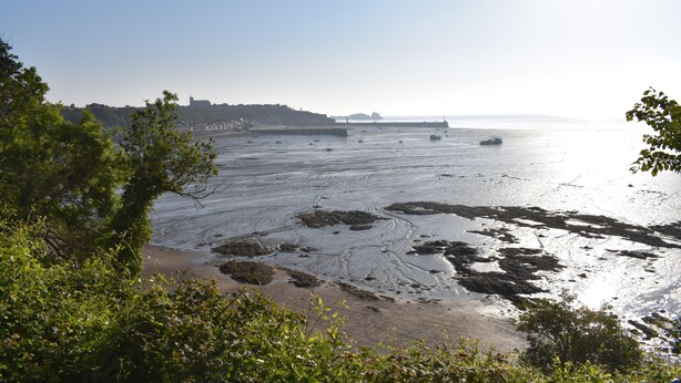 A coastal view with a sandy beach, rocky areas, and boats on the water. - Fisherman's house on the heights of Cancale (Cancale)
