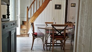 A wooden staircase leading to a dining area with a table and chairs. - Fisherman's house on the heights of Cancale (Cancale)