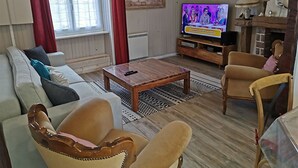A living room with a sofa, armchairs, a coffee table, a TV, and a fireplace. - Fisherman's house on the heights of Cancale (Cancale)