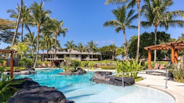 A pool area with clear water, surrounded by rocks and palm trees. - Includes Mauna Lani Beach Club Pass.  Golf Villa at Mauna Lani D3 (Waimea)