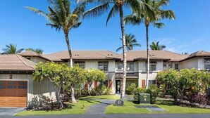 A two-story residential building with a garage, palm trees, and a well-maintained lawn. - Includes Mauna Lani Beach Club Pass.  Golf Villa at Mauna Lani D3 (Waimea)