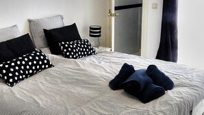 Ein Schlafzimmer mit einem Bett, Kissen, einem Nachttisch und einer Tür.