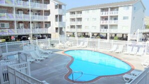 A swimming pool surrounded by white lounge chairs and a white fence. - Two bedroom, with pool, close to Seacrets! (Ocean City)