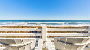 Une vue sur la plage avec des chaises blanches et une clôture en bois.