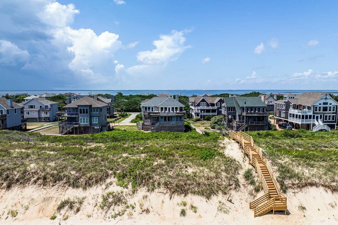 Une propriété située en bord de mer, comprenant plusieurs maisons reliées par une promenade en bois.
