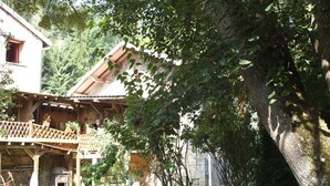 Ein rustikales Holzhaus mit Balkon, umgeben von viel Grün und Bäumen.